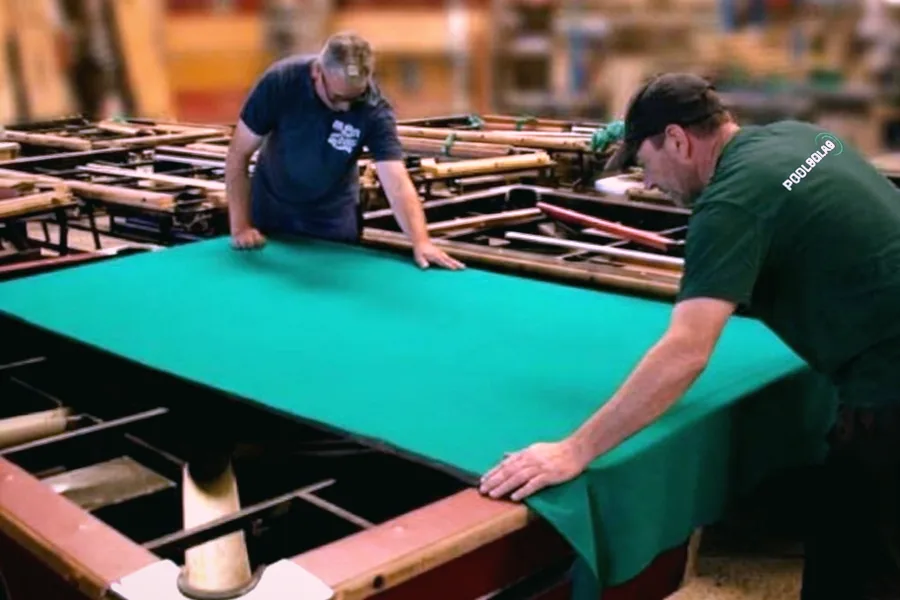 Técnicos de Pool Bola 8 estirando el paño de una mesa en el taller